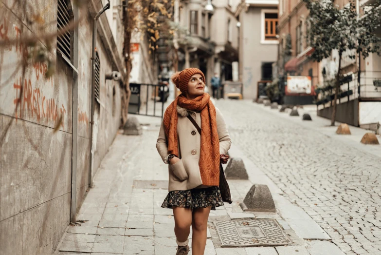 a person with a scarf and hat walking down a city street