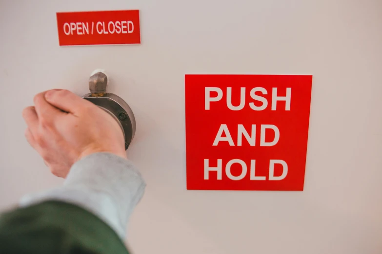 a person placing soing on a wall with a red sign