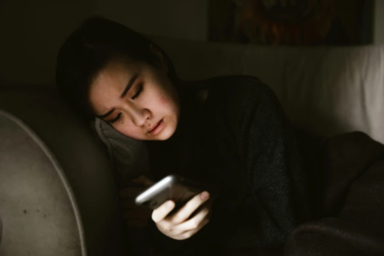 a woman is laying on the couch holding a remote control