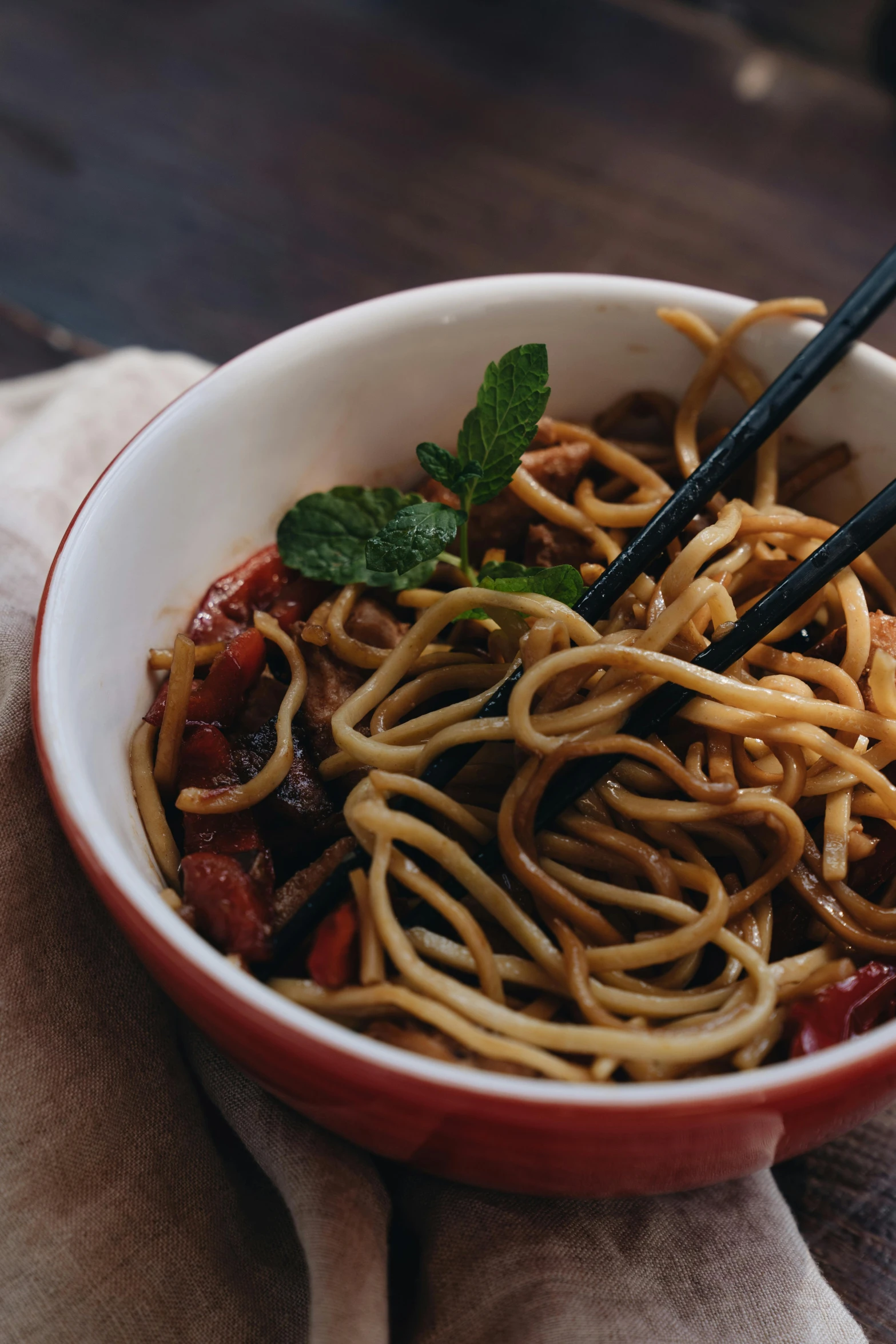 a bowl filled with noodles and chopsticks on top of a napkin