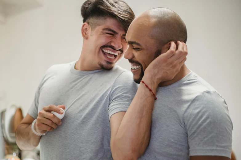 two men smile while holding their hair dryers