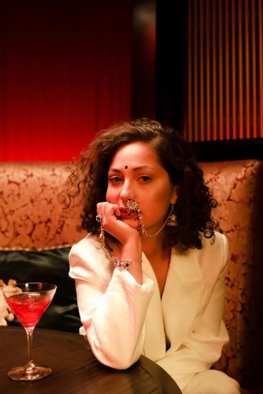 a woman in a suit, necklaces, and earrings smoking a cigarette