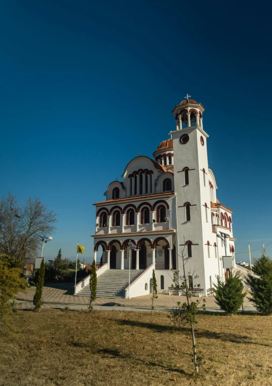 a very tall building with multiple windows and steeple in a green field