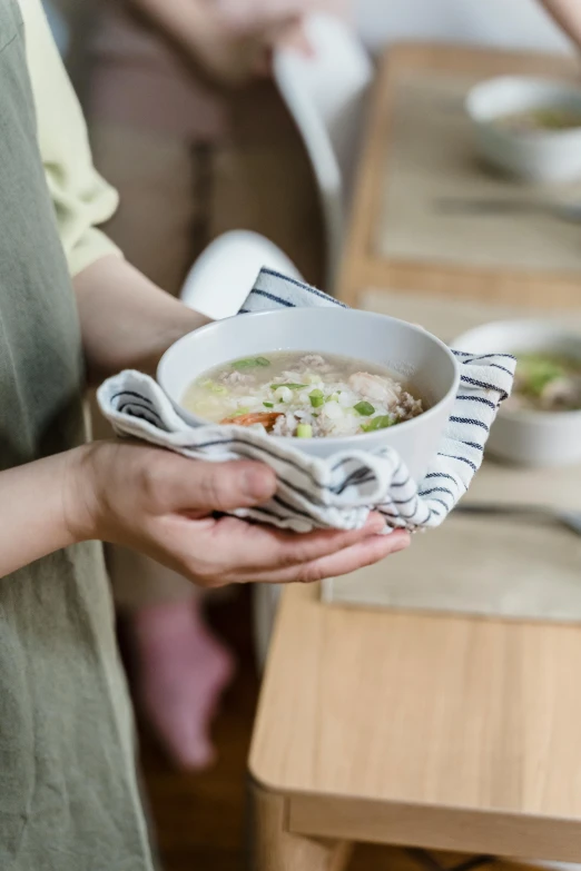 woman holding plate of soup in a bowl