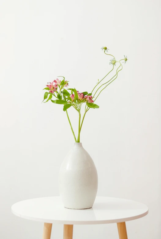 the small white vase has flowers in it