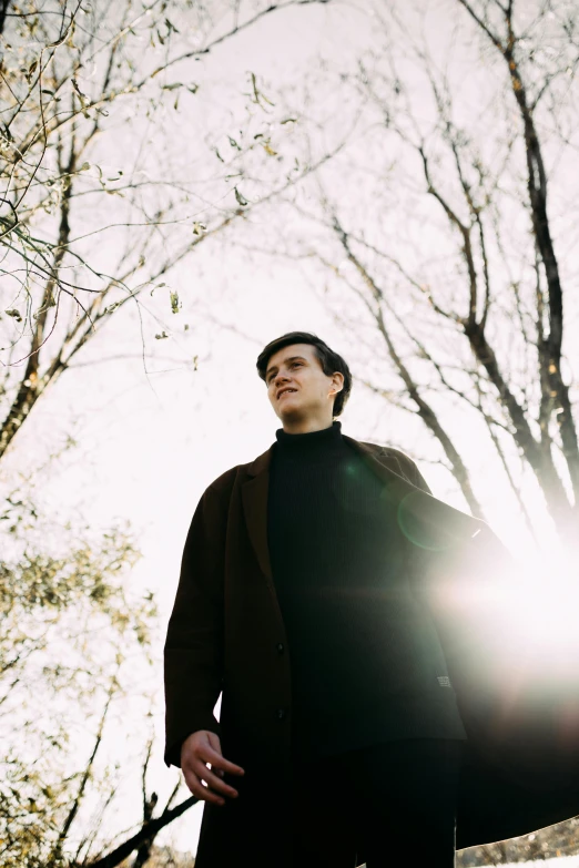 a man is standing near trees smiling at the sun