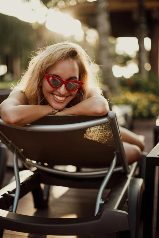 the woman in sunglasses smiles while she sits down