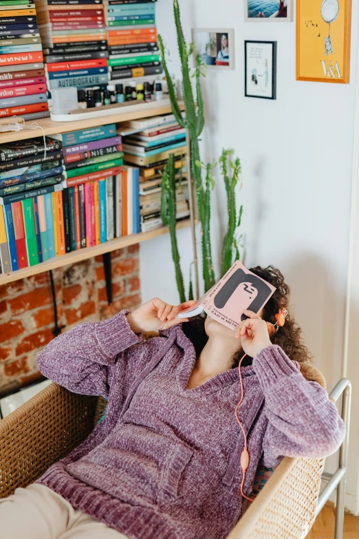 a girl laying down with a pink book in her mouth