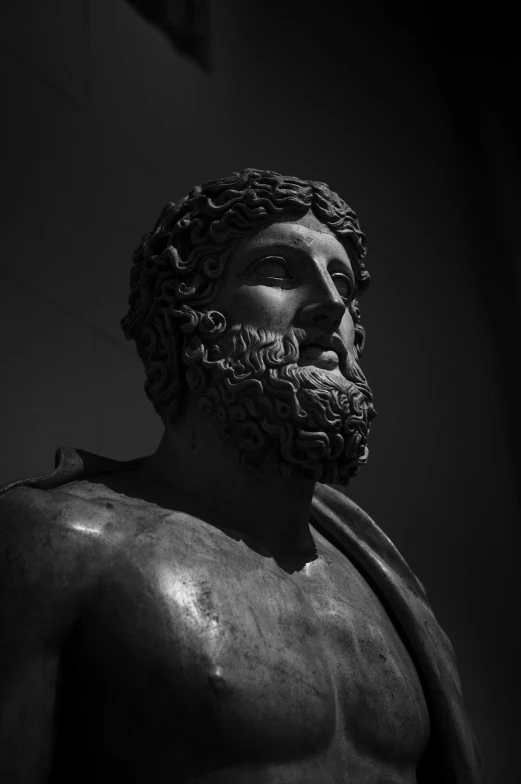 a statue of a greek roman god stands in the dark