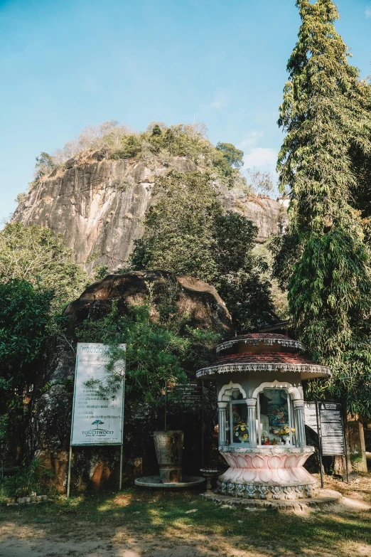 the small white building has trees and a mountain in the background