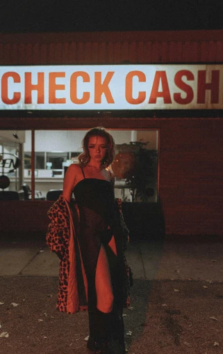a woman posing for the camera in front of a check cash
