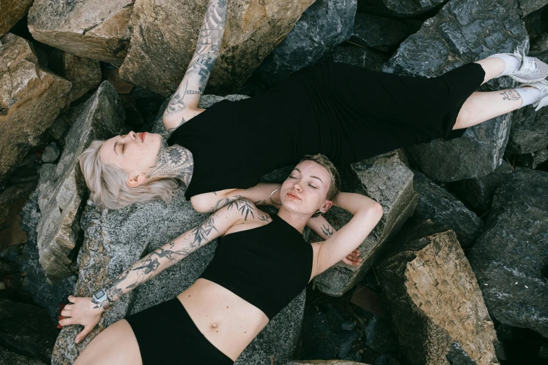 two women laying on some rocks and one is holding onto another