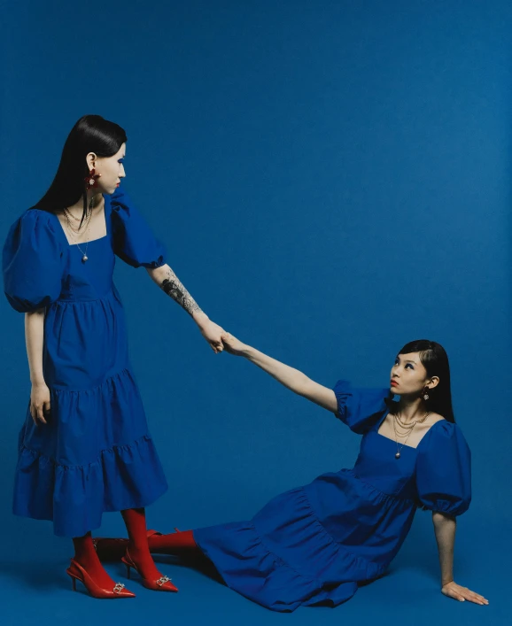 two girls in blue dresses touching each other with their hands