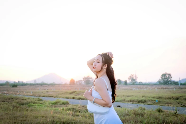 the woman has her hands in her hair standing by a dirt road