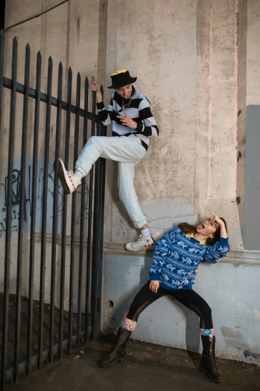 two young men, one with cowboy hats, standing by black metal fence