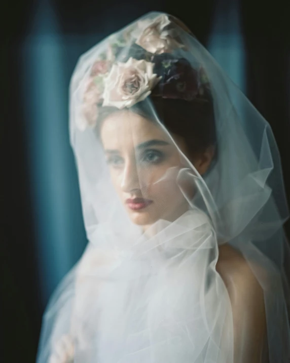 woman in bridal gown and veil standing with flower in hair