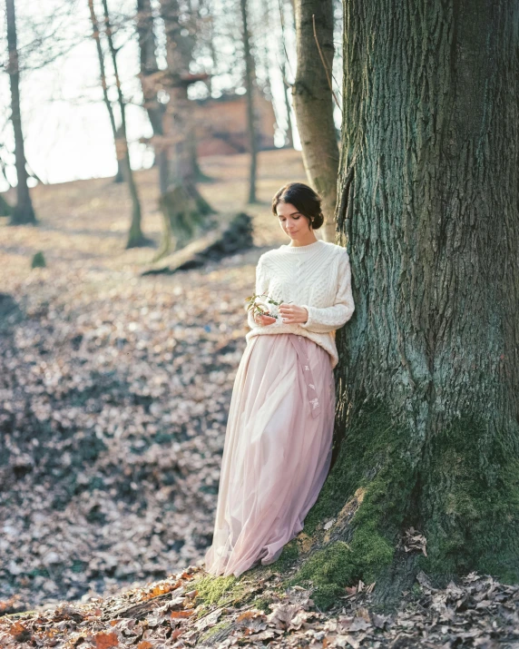 a woman leaning against a tree in the fall