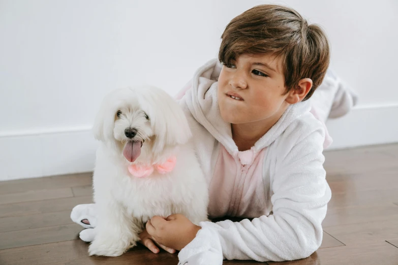 a boy in pink shirt holding a white dog