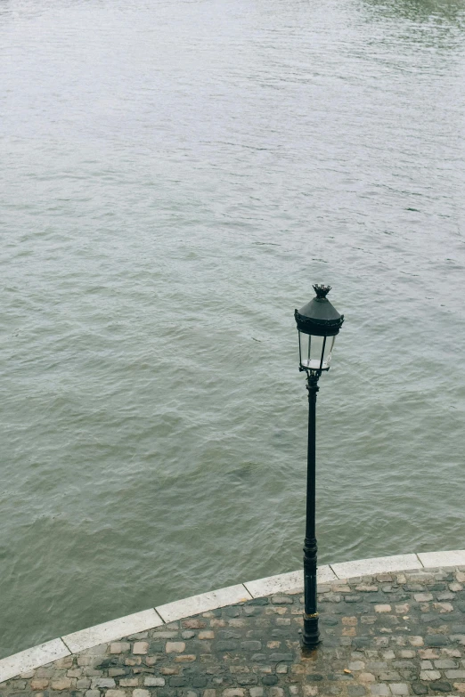 a lamp post next to the water at dusk