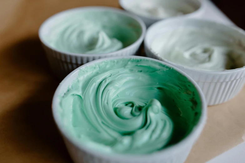 four cups filled with green and white desserts