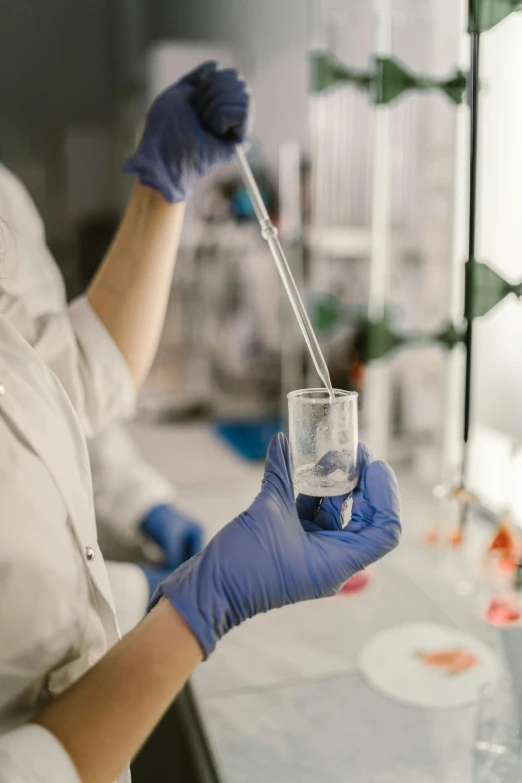 a scientist holding a beakle with liquid and a stick