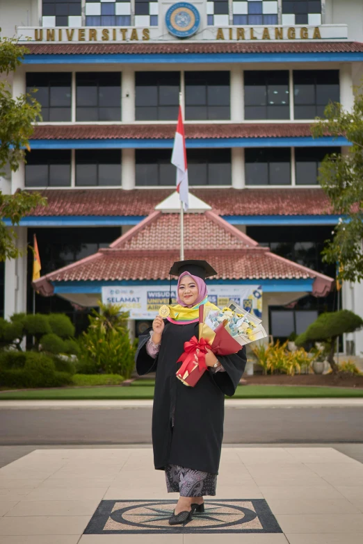 a woman wearing a graduation gown is carrying two bags