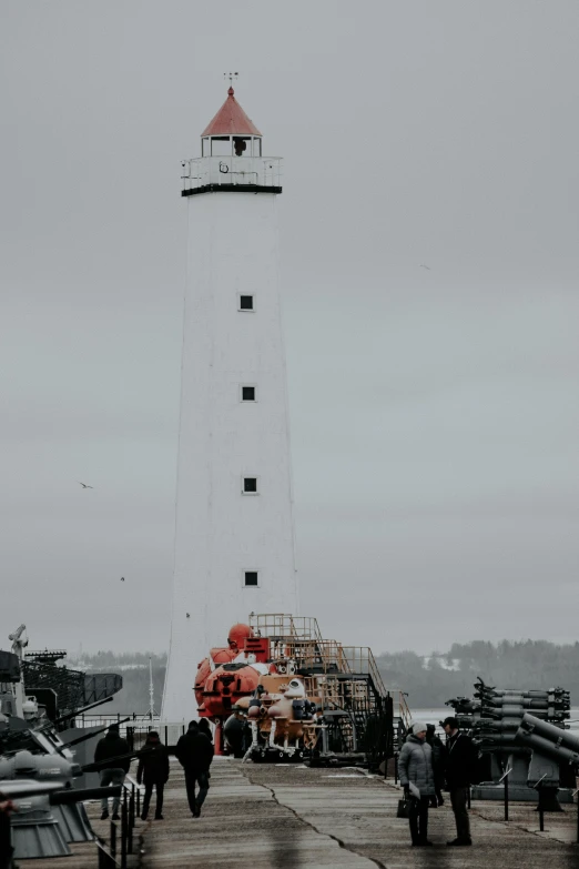 a pier has a light house and people walking on it