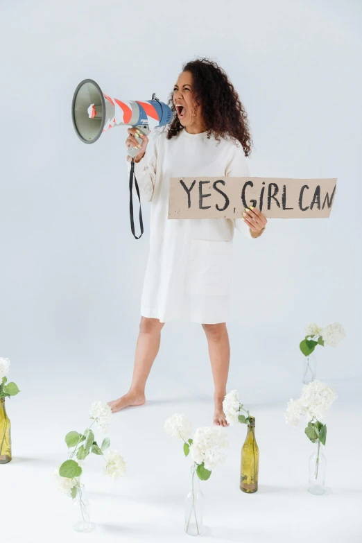 a woman holding a paper sign and talking into a megaphone