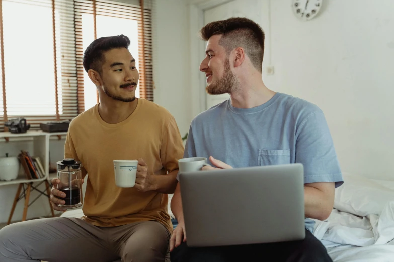 a couple of people sitting on top of a bed with a laptop