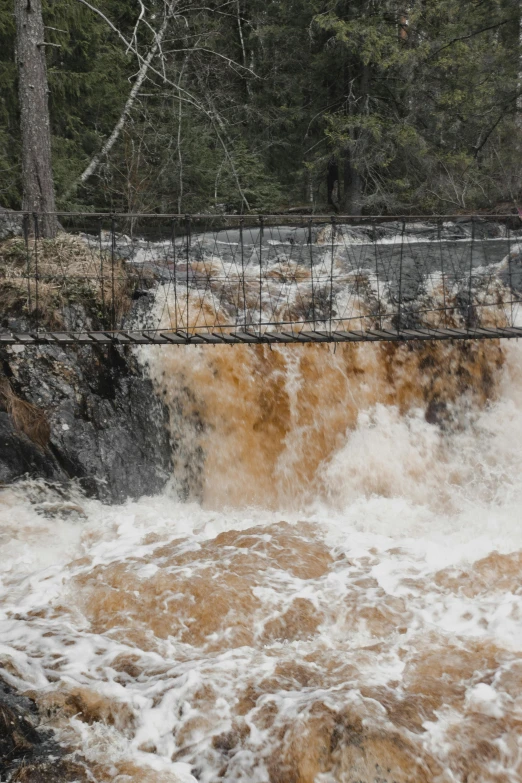 a man standing on a bridge over water next to a waterfall