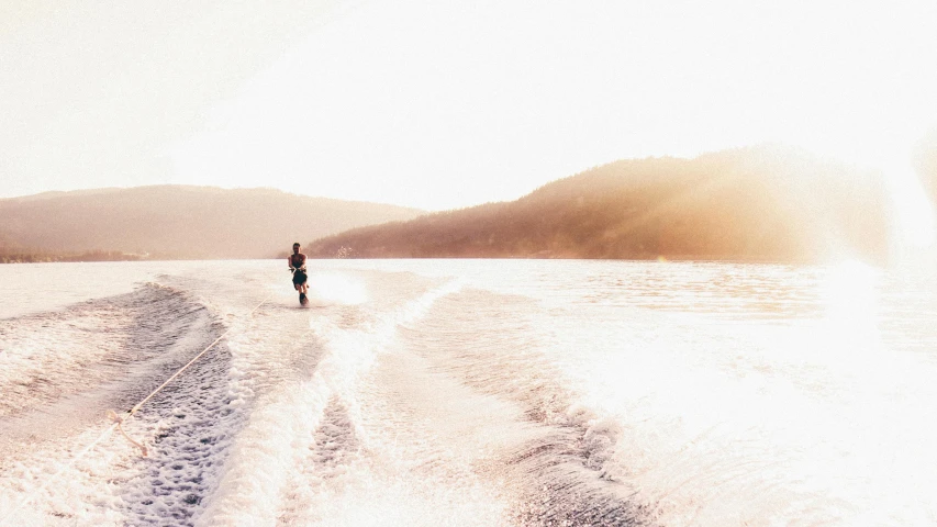 an individual walking on the water near some hills