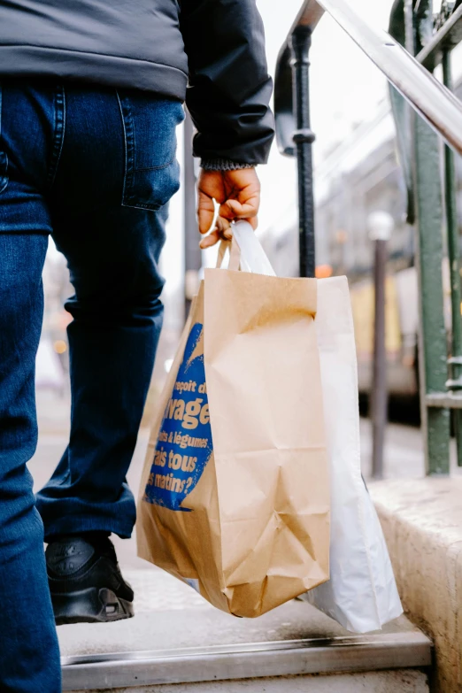 a man in black jacket holding shopping bags on steps