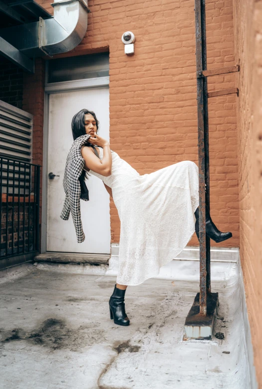 a woman in white poses near a building