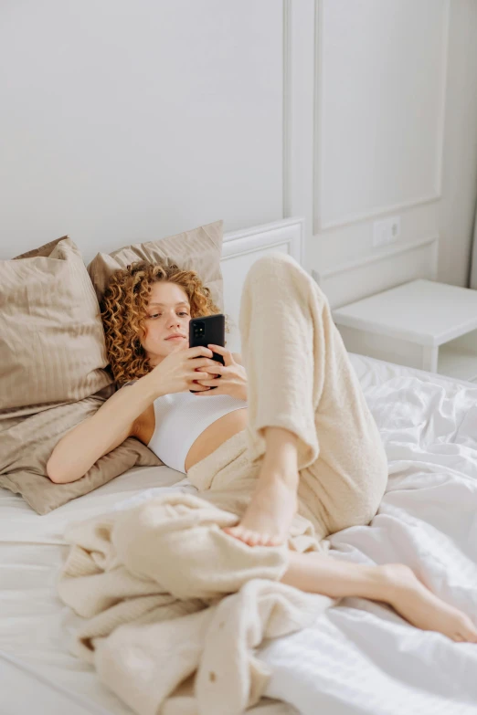 a woman laying on a bed while looking at a cell phone