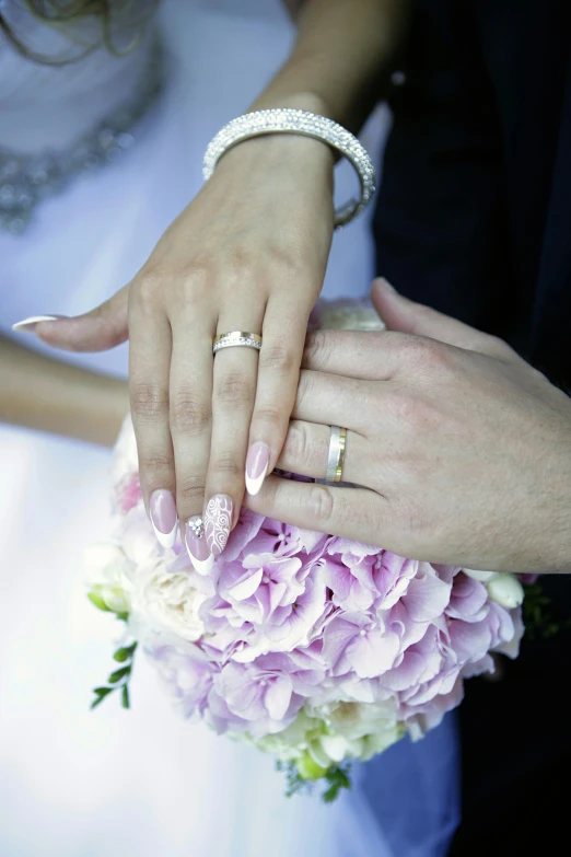 two people with wedding rings and bouquet