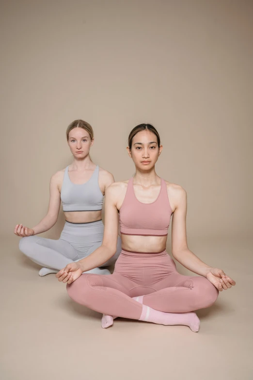 two females sitting in front of each other in yoga outfits