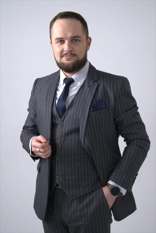 a bearded man in a suit and tie poses