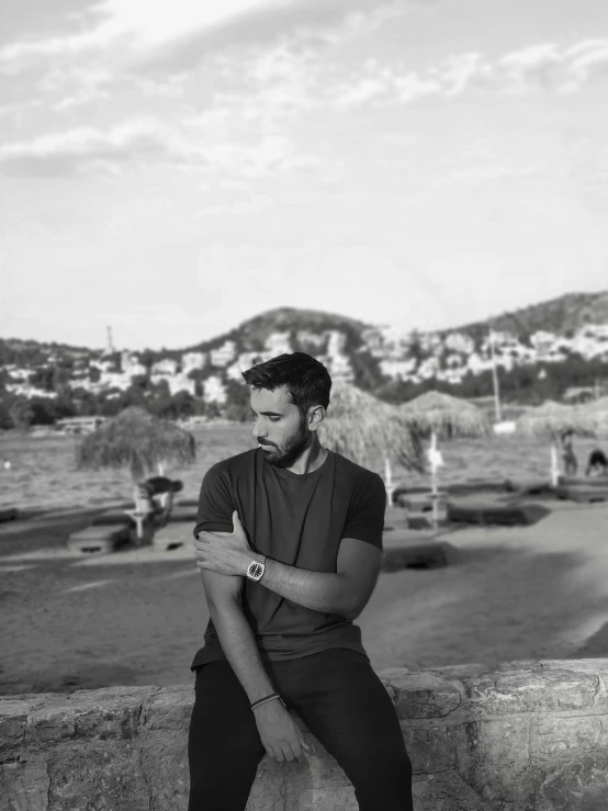 a man sitting on a wall while using his watch