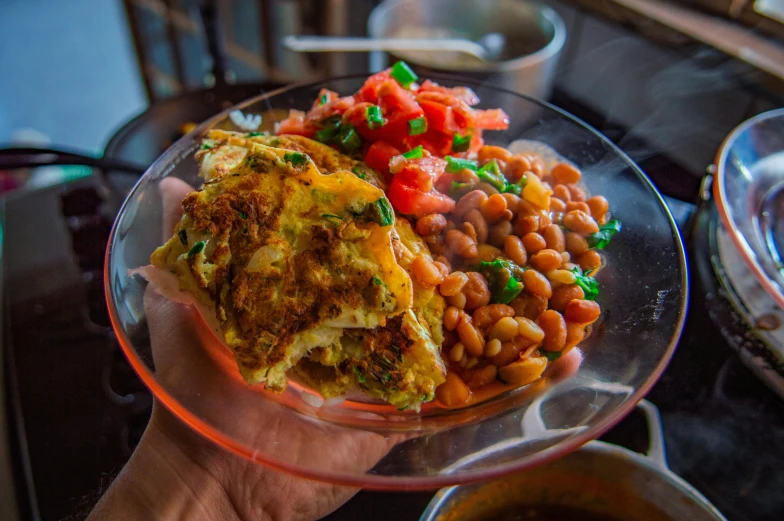 someone holding up a glass plate full of food