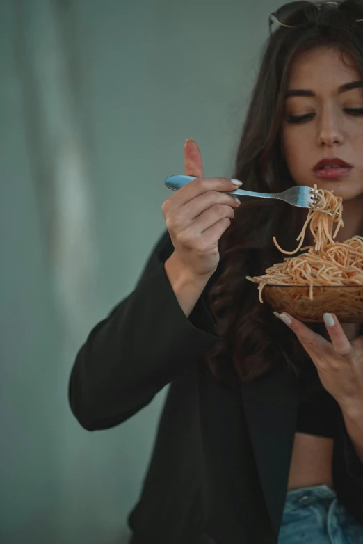 a woman eating spaghetti with the assistance of a fork and knife