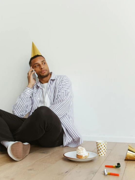 a man wearing a party hat talks on his cell phone