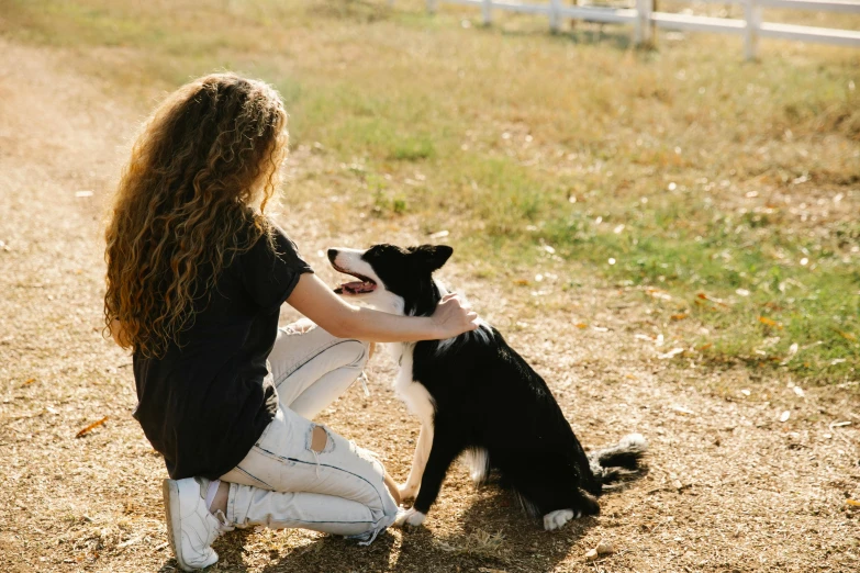 a woman is petting a dog in the dirt