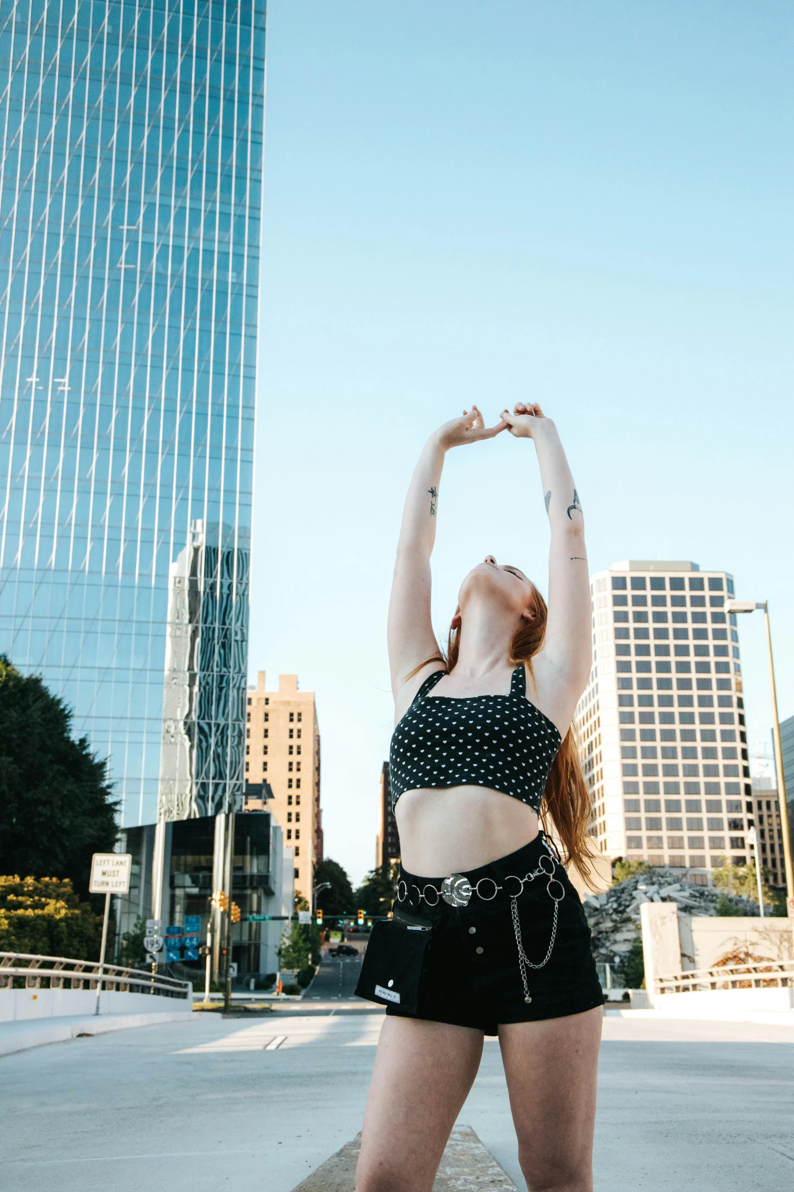 a young lady standing on a street corner with her hands up