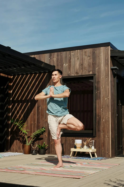 a man doing yoga outside a wooden building