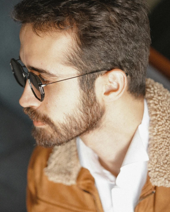 a man with glasses staring back while wearing a jacket and tie