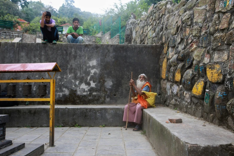 a man sitting next to a bunch of stone stairs