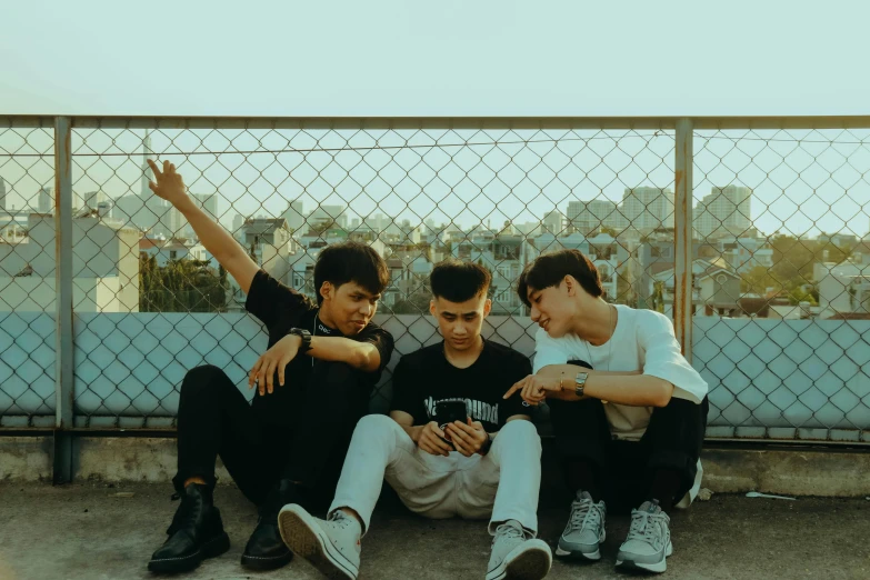 three boys sitting next to each other on a sidewalk