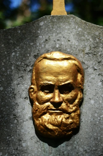 a gold head on the side of a stone