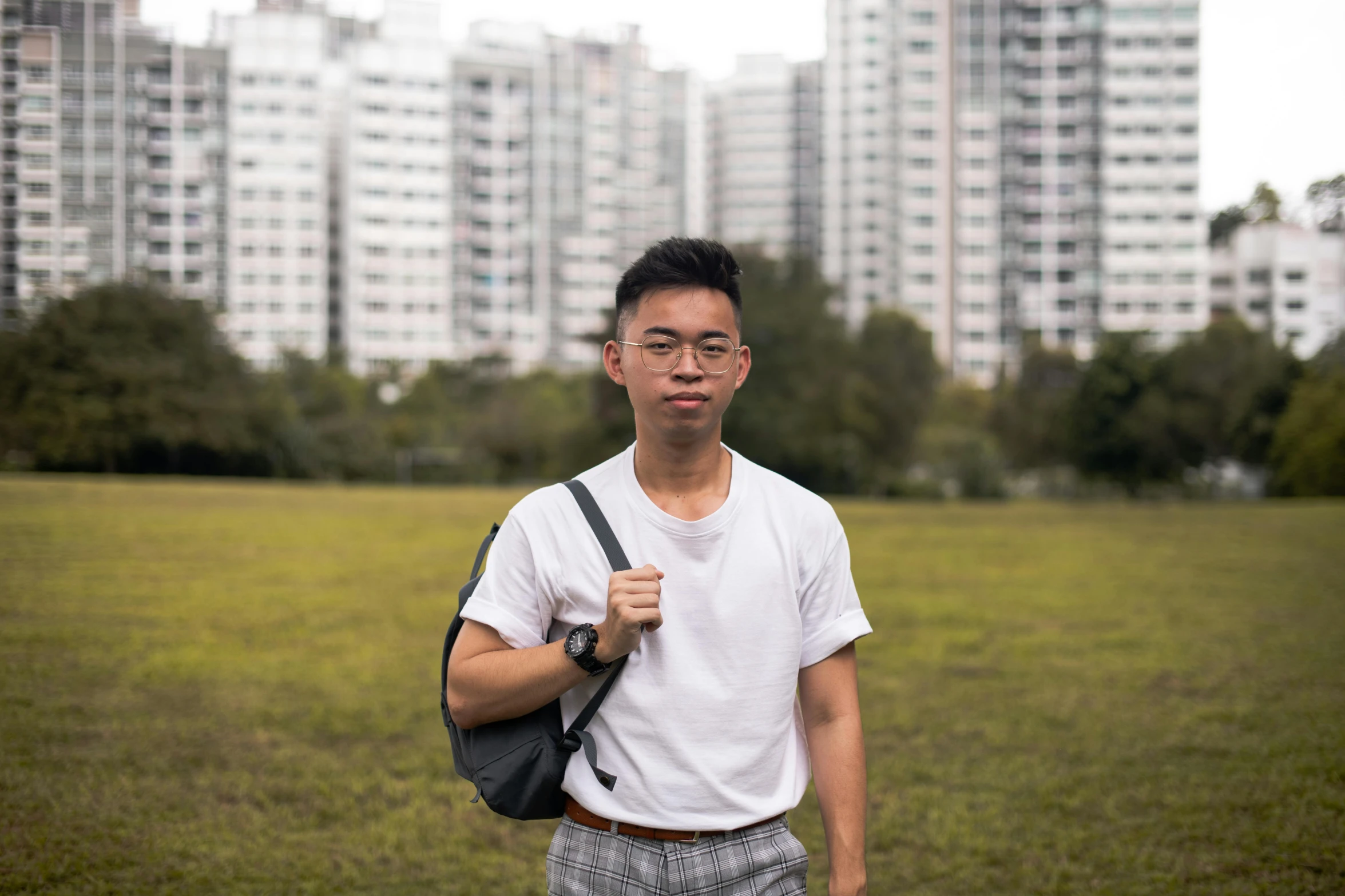 a young man posing for a pograph with buildings behind him