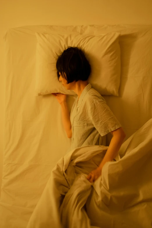 an asian boy with dark hair laying in a white bed